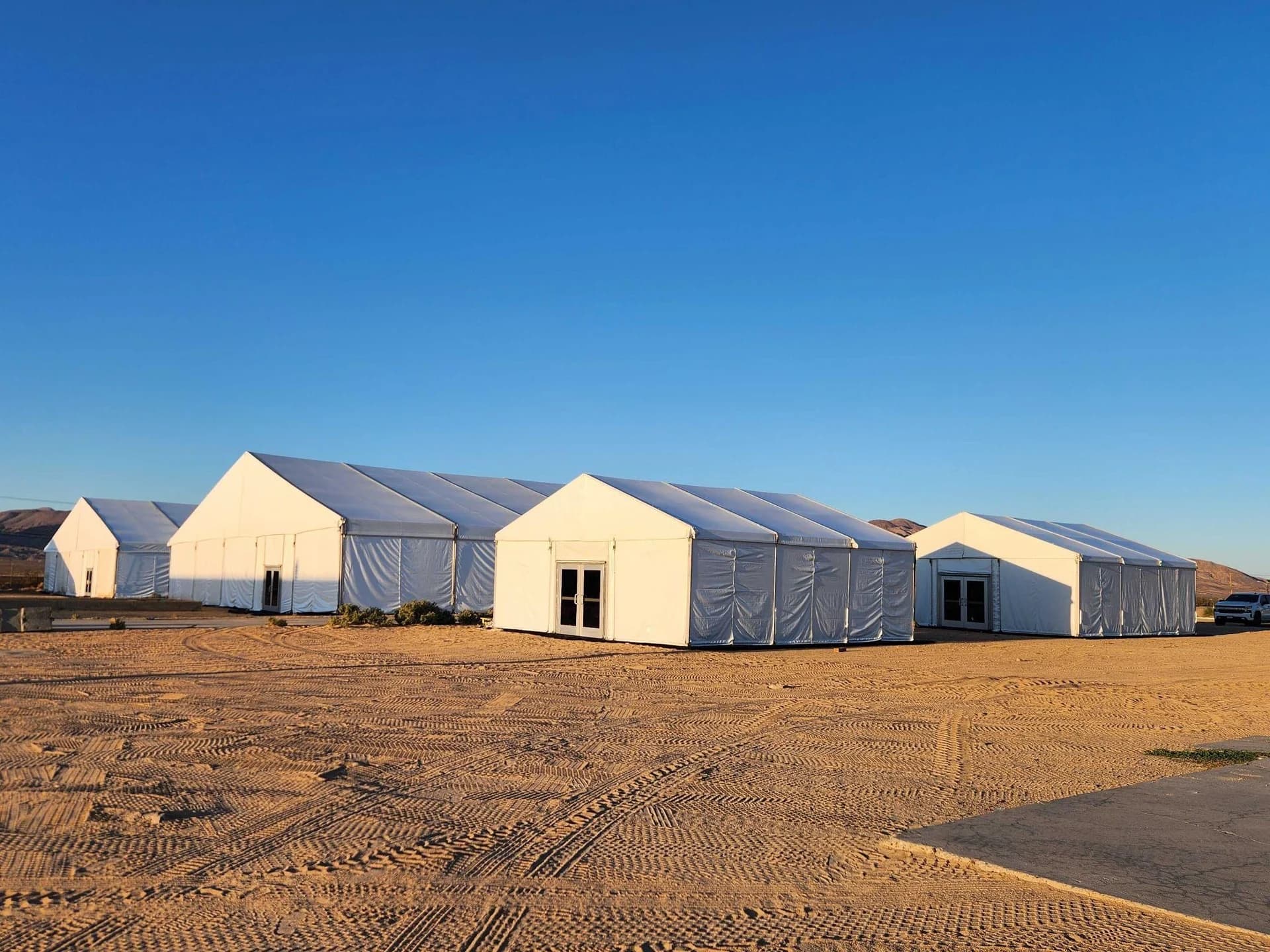 Rows of enclosed white temporary structures installed on an open site