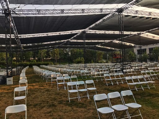 Large field covered by temporary canopies and filled with empty foldable chairs