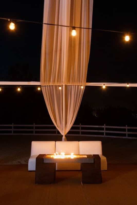 Nice outdoor white leather couch behind a fire inside a table