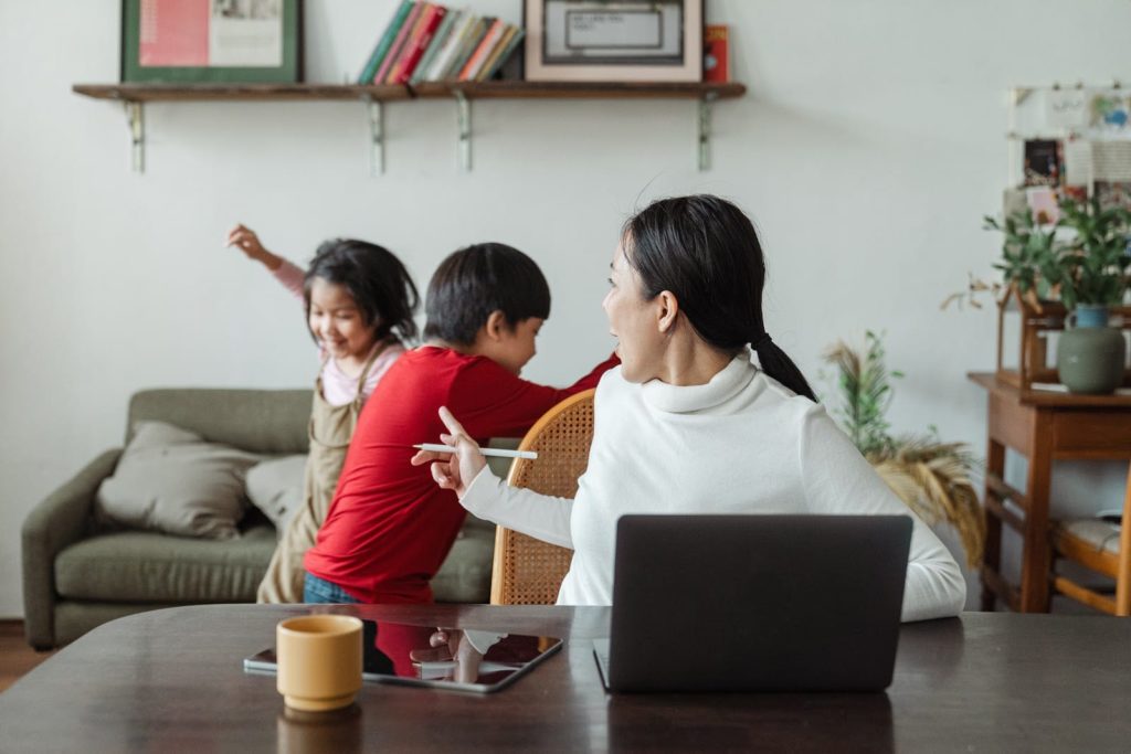 Two kids playing while mother is working from home